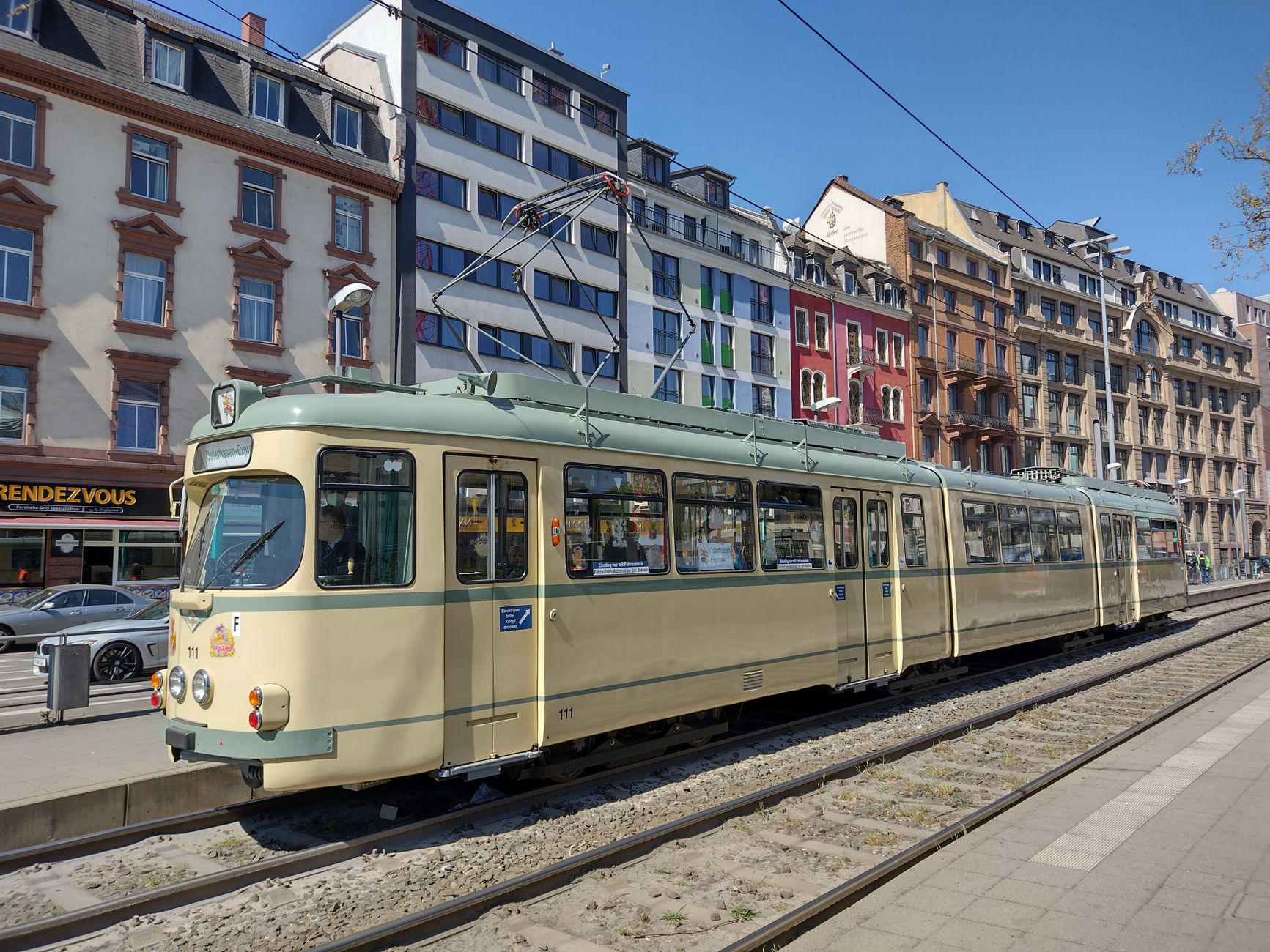 Cremefarbene historische Straßenbahn auf einer Frankfurter Straße vor Altbaufassaden